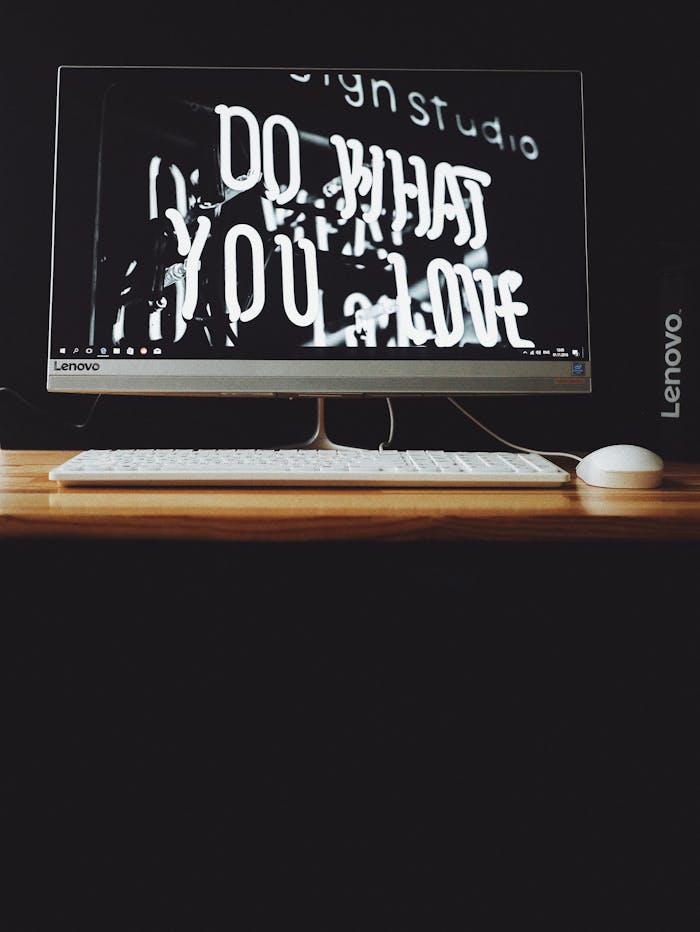 Lenovo desktop with keyboard and monitor displaying 'Do what you love' message. Ideal for creative workspace settings.